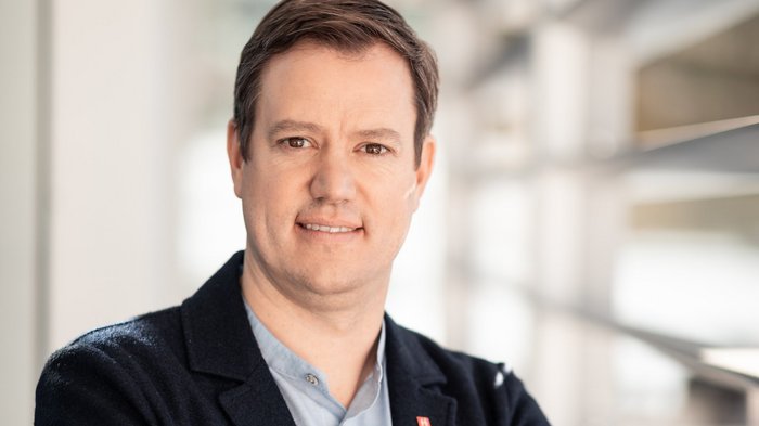 Martin Haller © Florian Andergassen Porträt eines lächelnden Mannes in Business-Kleidung mit verschränkten Armen