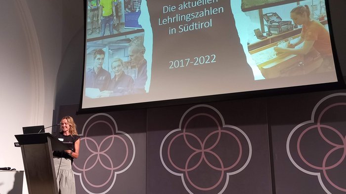 Europäisches Kammertreffen Frau präsentiert Lehrlingszahlen in Südtirol von 2017 bis 2022 auf einer Bühne.