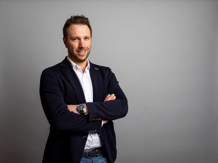 Wichtige Investitionen in Mörtel und Asphalt Geschäftsmann mit verschränkten Armen vor grauem Hintergrund