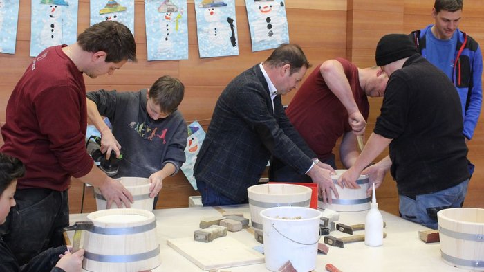 Tag des Handwerks in Jenesien Menschen arbeiten gemeinsam an Holzbottichen in einem Holzwerkstatt-Workshop