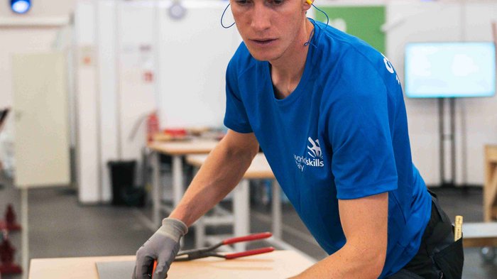 EuroSkills 2023: adesso bisogna concentrarsi! Giovane uomo misura lastra di metallo con metro in laboratorio