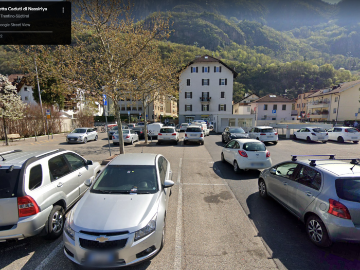 Flächenverbrauch auf Rekordhöhe in Italien – auch in Südtirol anhaltender Anstieg Parkplatz mit Autos vor Wohngebäuden und Bergkulisse in Bozen