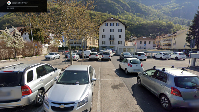 Flächenverbrauch auf Rekordhöhe in Italien – auch in Südtirol anhaltender Anstieg Parkplatz mit Autos vor Wohngebäuden und Bergkulisse in Bozen