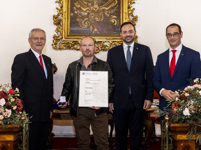 Südtiroler Wirtschaftspreis 2024 Vier Männer bei Preisverleihung, einer hält Urkunde und Medaille