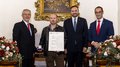 Südtiroler Wirtschaftspreis 2024 Vier Männer bei Preisverleihung, einer hält Urkunde und Medaille