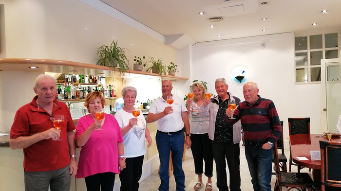 Badespaß an der Adria Gruppe von Senioren, die mit Aperol-Spritz in einem hellen Barraum anstoßen