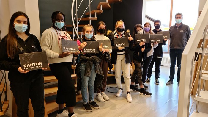 Mittelschule Neumarkt besichtigt Handwerksbetriebe und Hotels in Montan, Tramin und Auer Gruppe von Personen mit Masken hält Kanton Treppen Scale Schilder in modernem Innenraum