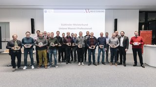 © Alan Bianchi Gruppenfoto von 20 Männern mit Auszeichnungen vor Südtiroler Meisterbund Projektion