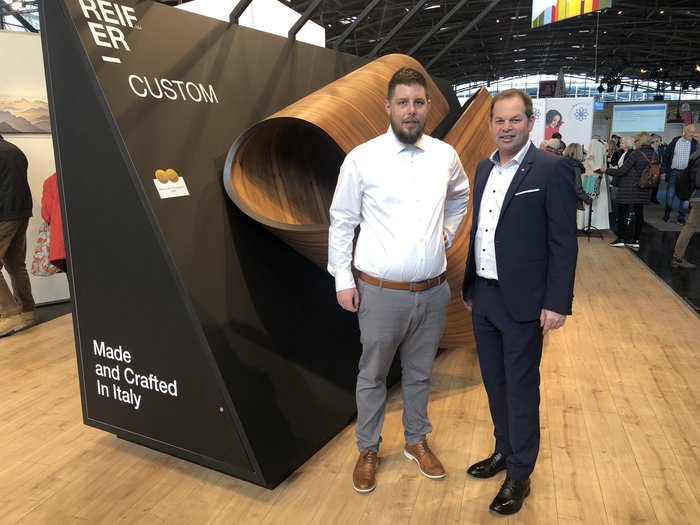 Zwei Südtiroler Unternehmen mit Bayrischem Staatspreis ausgezeichnet Zwei Männer stehen vor großem Holzkunstwerk auf Messe