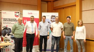 News Sechs Personen stehen vor Werbebannern in einem Konferenzraum