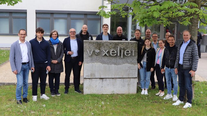 Maschinen- und Anlagenbau – Südtiroler Unternehmer/innen zu Besuch in Augsburg Gruppenfoto vor dem Voxeljet Firmenschild draußen