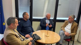 News Vier Männer sitzen um einen runden Tisch und führen ein Gespräch im Büro