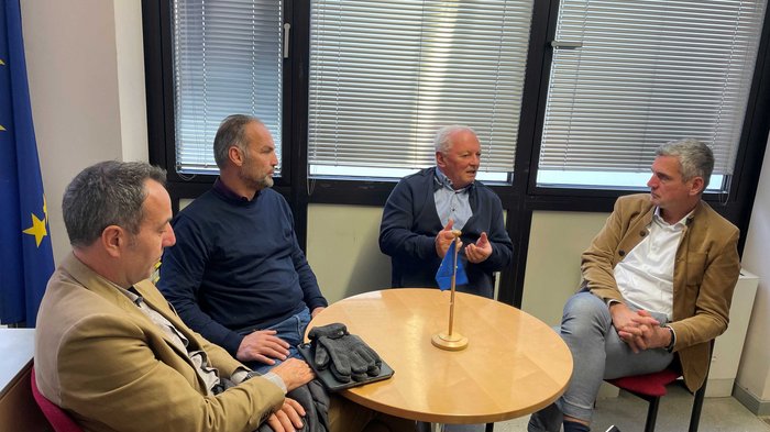 Antrittsbesuch bei dem EU-Abgeordneten Herbert Dorfmann Vier Männer sitzen um einen runden Tisch und führen ein Gespräch im Büro