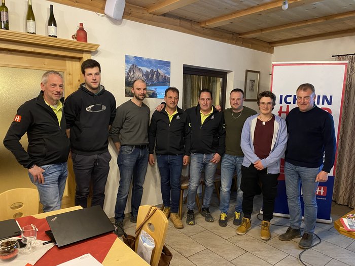 lvh-Kastelruth: Führung bleibt in Malerhänden Gruppe von acht Männern in einem Raum mit Tischen und Bannern im Hintergrund.