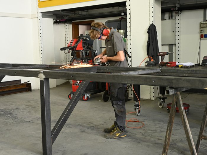 Mettersi all'opera con mani e cuore: l'apprendista fabbro Jakob Lantschner racconta la sua formazione artigianale Persona con protezione auricolare che leviga una struttura metallica in officina