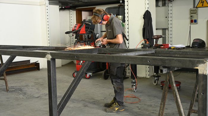 Mettersi all'opera con mani e cuore: l'apprendista fabbro Jakob Lantschner racconta la sua formazione artigianale Persona con protezione auricolare che leviga una struttura metallica in officina