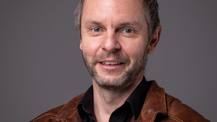 Grande interesse per gli appalti pubblici in Val Pusteria Ritratto di uomo sorridente con giacca di pelle marrone su sfondo grigio