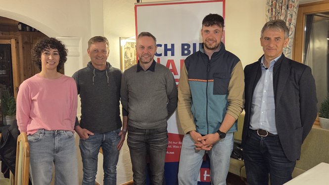 Fünf Personen stehen vor Banner in Zimmer bei Veranstaltung