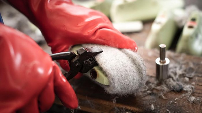 Junghandwerker/innen im lvh und Hoteliers- und Gastwirtejugend (HGJ) zu Gast in der Mittelschule der Ursulinen in Bruneck Person entfernt Filzwolle mit Zange von Schuhsohle