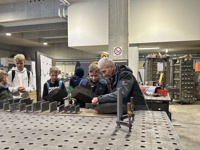 Giovani Artigiani di lvh.apa e Giovani Albergatori di HGJ in visita alla Scuola media di Vandoies Adulto mostra a ragazzi in officina come lavorare con stampi per metallo