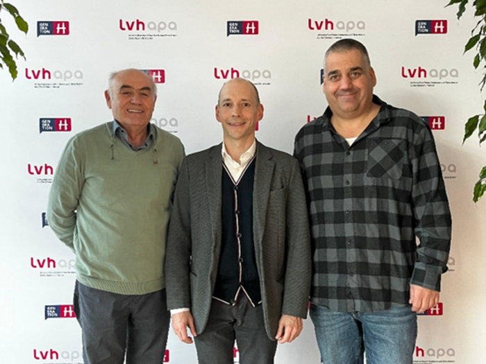 Soluzioni concrete per il foglio di servizio elettronico Tre uomini davanti a una parete pubblicitaria LVH APA, due sorridenti e uno neutro