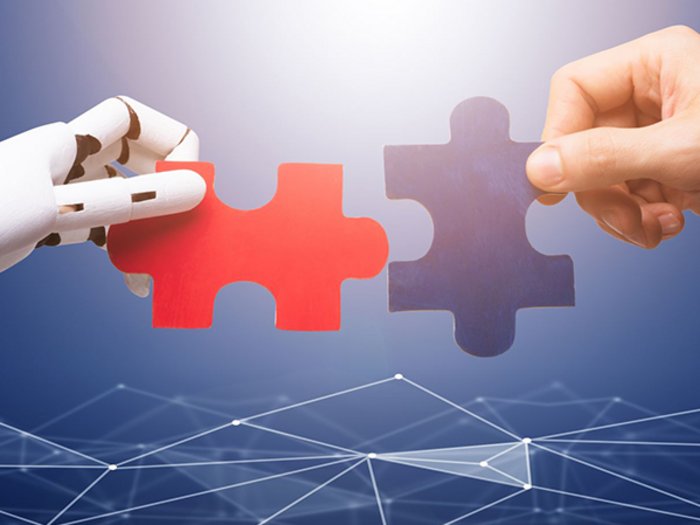 Digitalisierung: Der Mensch im Mittelpunkt Roboter- und menschliche Hand verbinden Puzzleteile vor digitalem Netz