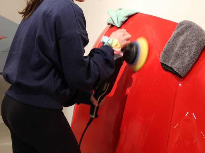 Una settimana intorno all‘artigianato Donna lucida una carrozzeria rossa con una macchina lucidatrice