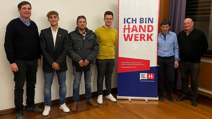 Junghandwerker übernimmt in Tramin Sechs Männer stehen neben einem Banner mit der Aufschrift Ich bin Handwerk.