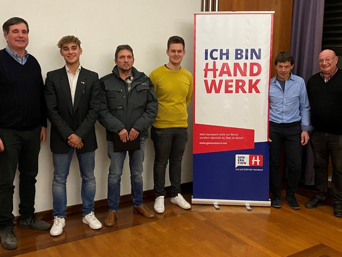 Junghandwerker übernimmt in Tramin Sechs Männer stehen neben einem Banner mit der Aufschrift Ich bin Handwerk.