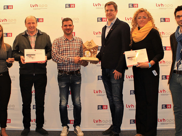 Sport und Handwerk: ein Volltreffer Sechs Personen bei einer Preisverleihung mit Urkunden und Trophäe vor lvhapa Hintergrund