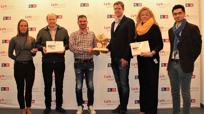 Sport und Handwerk: ein Volltreffer Sechs Personen bei einer Preisverleihung mit Urkunden und Trophäe vor lvhapa Hintergrund