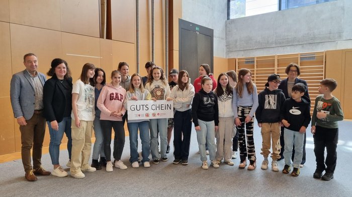 Schulprojekt "Clever gebaut": Selbst entwickelte Spiele prämiert Gruppe von Jugendlichen mit Erwachsenen hält einen Gutschein in einer Halle