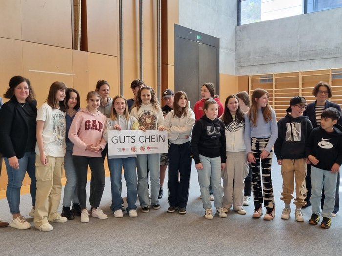 Schulprojekt "Clever gebaut": Selbst entwickelte Spiele prämiert Gruppe von Jugendlichen mit Erwachsenen hält einen Gutschein in einer Halle