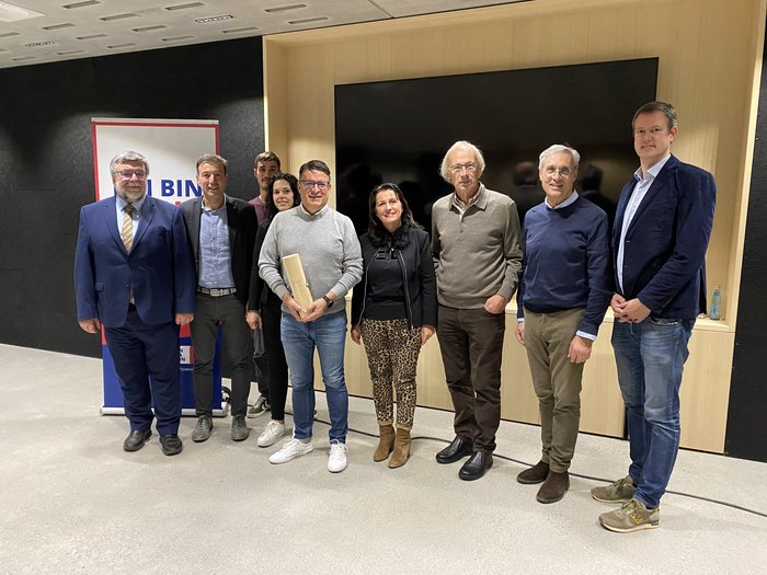 Gemeinsame lvh-Bezirksversammlung Ober- und Untervinschgau: Zusammenhalt und Zukunft im Fokus Gruppe von neun Personen steht vor Wand mit Fernsehbildschirm und Banner