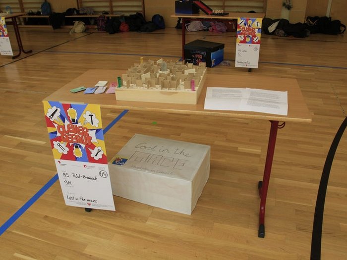 Kreative Spielideen: Preisverleihung für "Clever gebaut" Ein Holzlabor mit einem Labyrinth und Papier auf einem Tisch in einer Turnhalle.