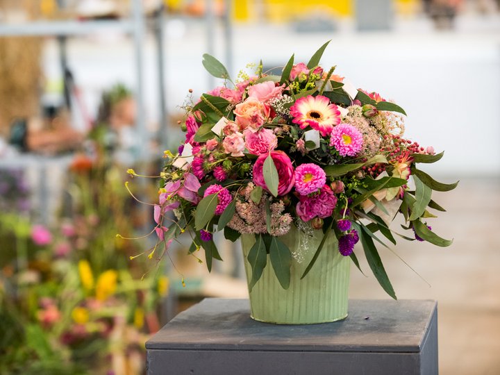 Fioristi Composizione floreale colorata in vaso verde su base grigia