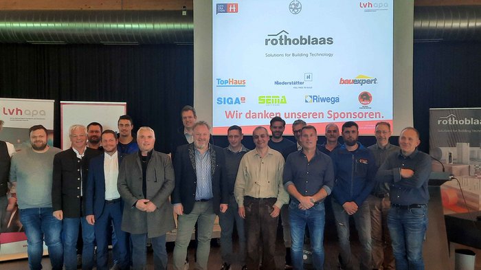 Obmann bestätigt Gruppenfoto von Männern vor Sponsorenwand bei Rothoblaas Veranstaltung