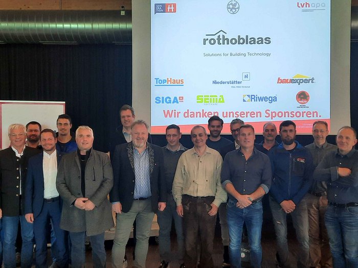 Obmann bestätigt Gruppenfoto von Männern vor Sponsorenwand bei Rothoblaas Veranstaltung
