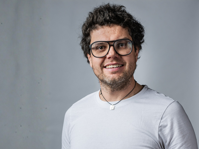 70 anni e non 20: Cosa racconta un paragrafo apparentemente insignificante sul valore delle immagini Uomo sorridente con occhiali e maglietta bianca su sfondo grigio