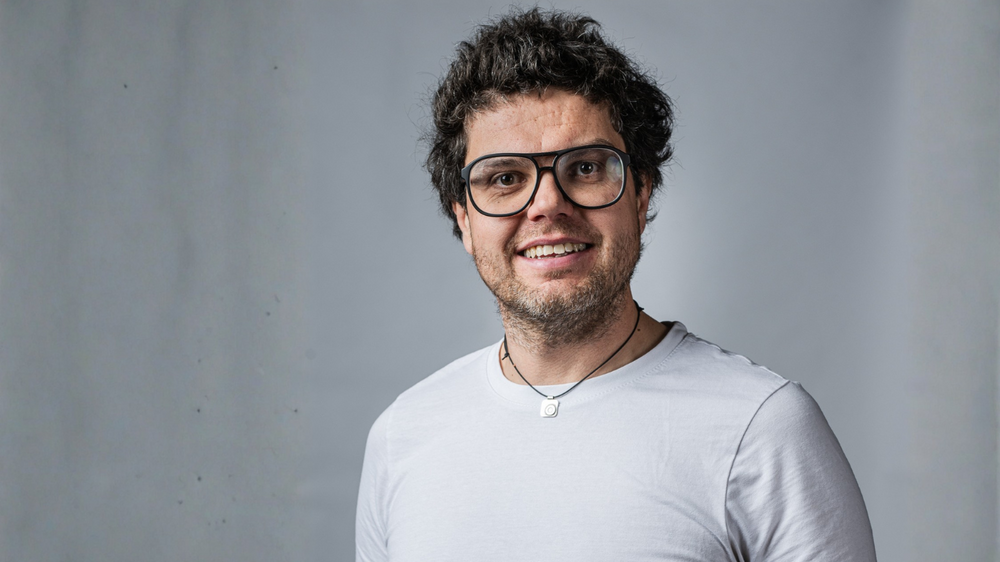 Home Lächelnder Mann mit Brille und weißem T-Shirt vor grauem Hintergrund