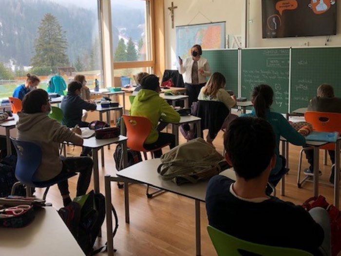Welcher Beruf passt zu mir? Schüler im Klassenzimmer mit Lehrerin vor Tafel und Bergblick