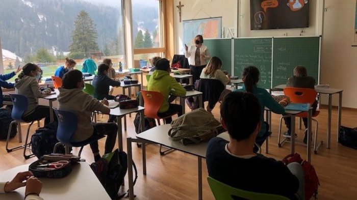 Welcher Beruf passt zu mir? Schüler im Klassenzimmer mit Lehrerin vor Tafel und Bergblick
