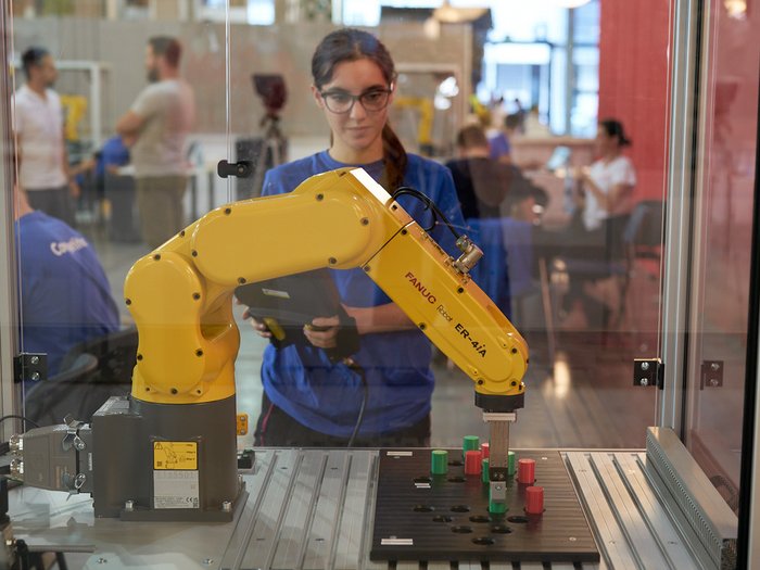 Handwerk live: Junge Talente zeigen, was sie draufhaben Frau bedient gelben Industrieroboter bei Schulungsübung in Werkstatt