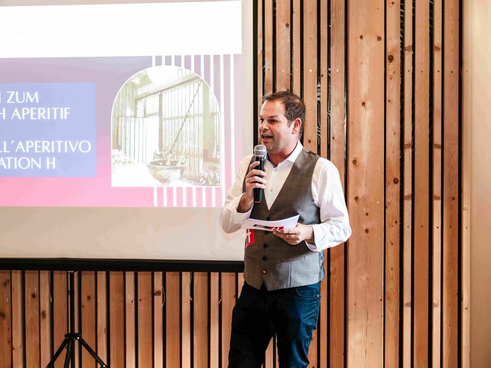 Consegna della spilla d’oro di lvh.apa Uomo con microfono davanti a schermo di proiezione durante presentazione