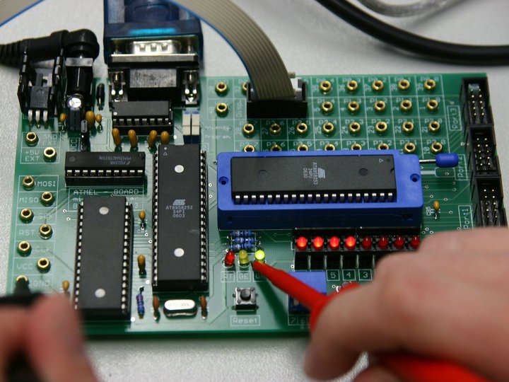 Ausbildung Hand hält Messspitze an leuchtende LEDs auf einer grünen Leiterplatte