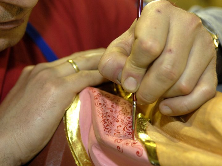 Policromatori e doratori Uomo dipinge motivi dettagliati su oggetto dorato e rosa con pennello
