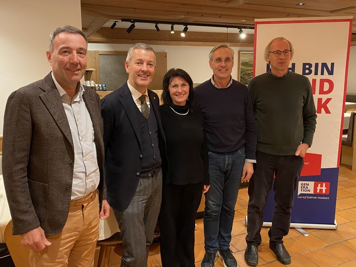 Serata informativa a Malles Venosta: focus su pianificazione territoriale e promozione dei giovani talenti Cinque persone insieme davanti a uno striscione pubblicitario in ambiente interno