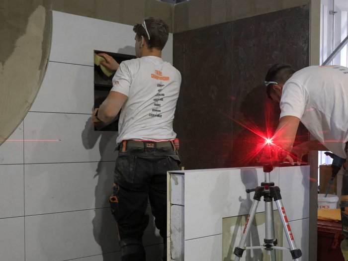 PCI-Alpencup 2023 - Wettkampf der Fliesenleger/innen Zwei Handwerker verlegen Fliesen und verwenden Lasertechnik für Präzision