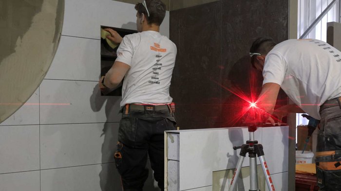 PCI-Alpencup 2023 - Wettkampf der Fliesenleger/innen Zwei Handwerker verlegen Fliesen und verwenden Lasertechnik für Präzision