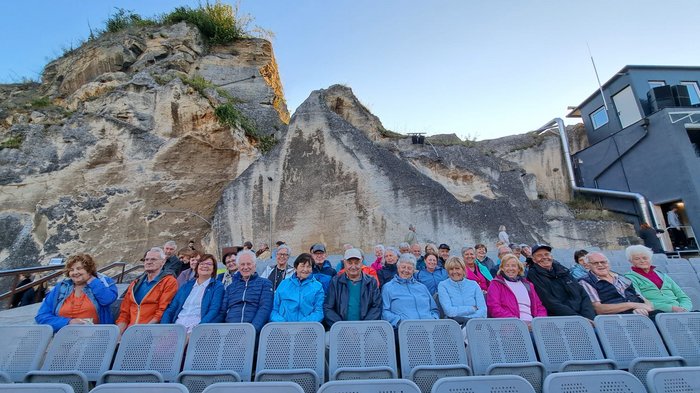 Viaggio culturale nel Burgenland – Opera e musical come fulcro del programma Anziani seduti su file di sedie davanti a una parete rocciosa in teatro all'aperto